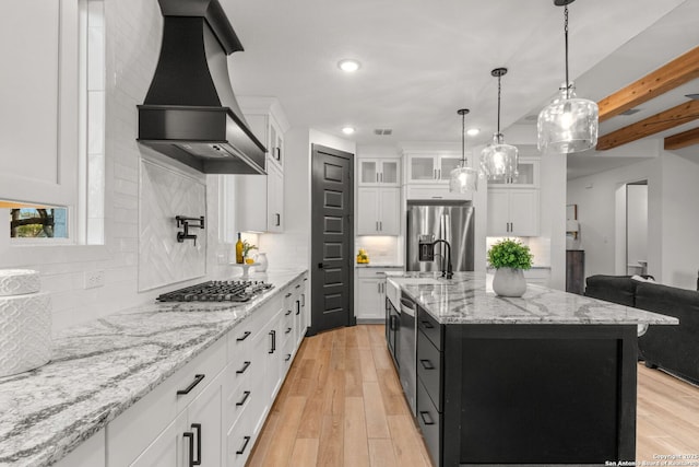 kitchen featuring white cabinetry, stainless steel appliances, an island with sink, and premium range hood