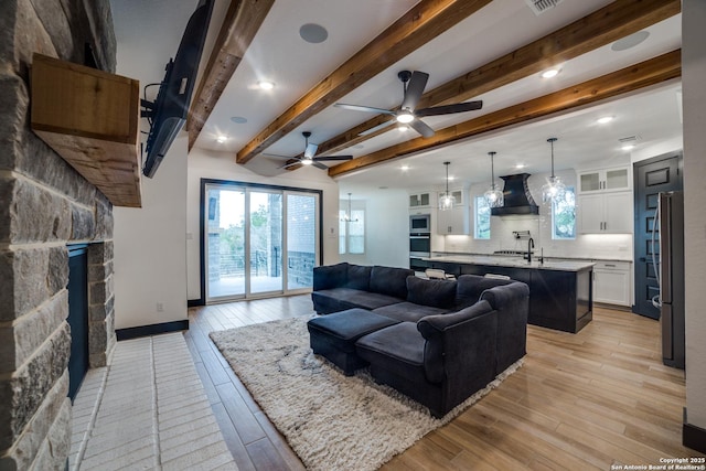 living room featuring beam ceiling, ceiling fan, sink, and light hardwood / wood-style floors