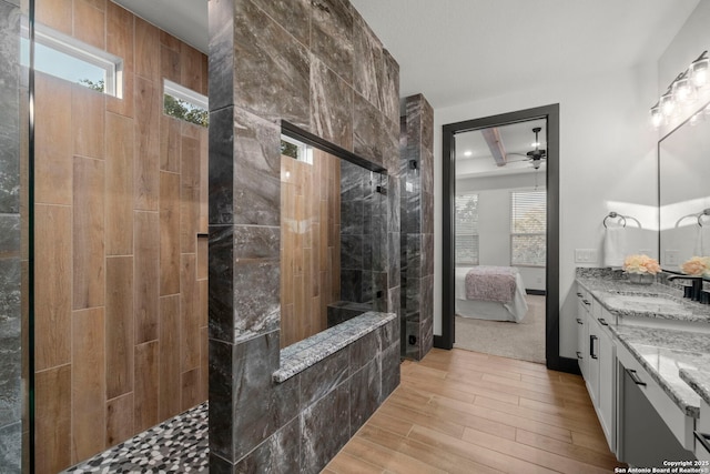 bathroom featuring hardwood / wood-style flooring, tiled shower, vanity, and ceiling fan