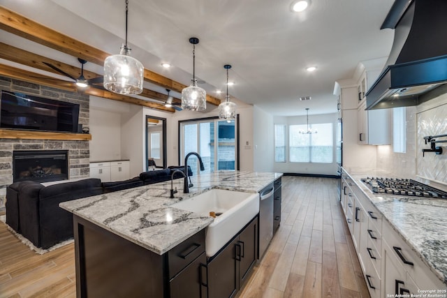 kitchen with an island with sink, premium range hood, sink, and white cabinets