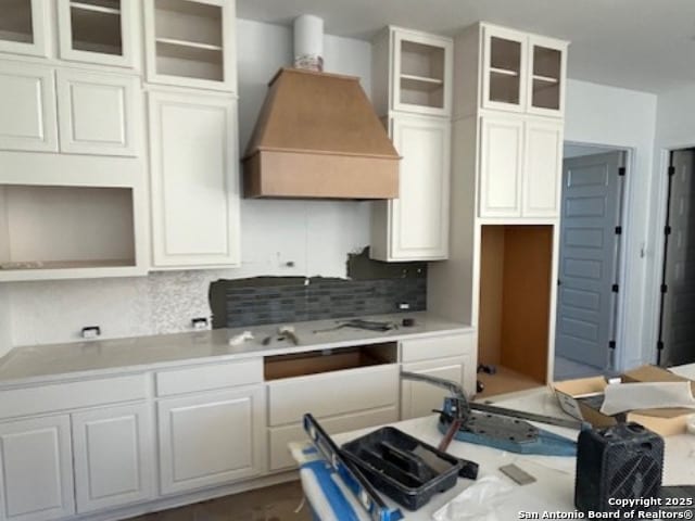 kitchen with white cabinets, tasteful backsplash, and premium range hood