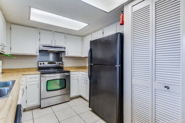 kitchen with stainless steel range with electric cooktop, a textured ceiling, light tile patterned floors, black refrigerator, and white cabinets