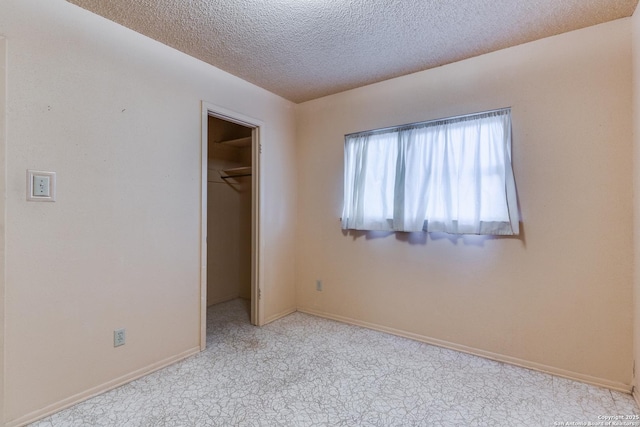 unfurnished bedroom with a closet, a spacious closet, light colored carpet, and a textured ceiling