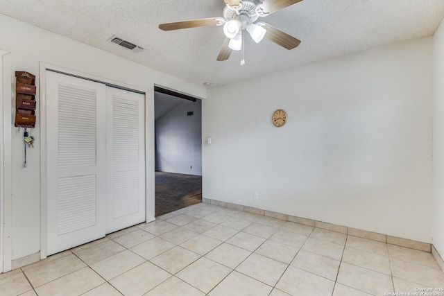 unfurnished bedroom featuring light tile patterned flooring, ceiling fan, a textured ceiling, and a closet