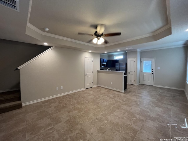 unfurnished living room featuring ceiling fan, a tray ceiling, and ornamental molding