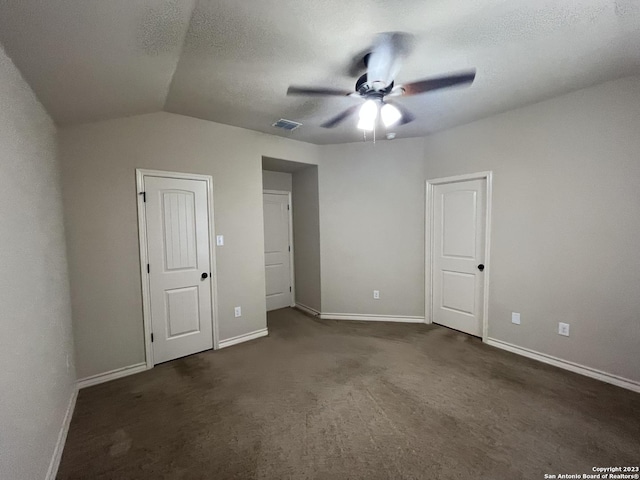 unfurnished bedroom with dark carpet, a textured ceiling, ceiling fan, and vaulted ceiling