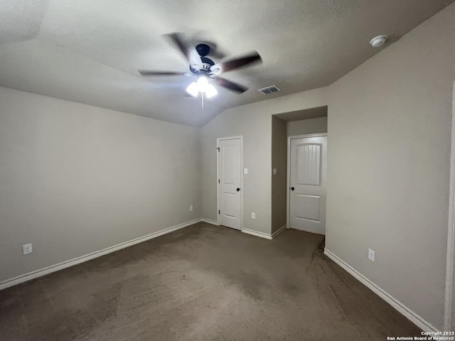 unfurnished bedroom with ceiling fan, lofted ceiling, a textured ceiling, and dark colored carpet