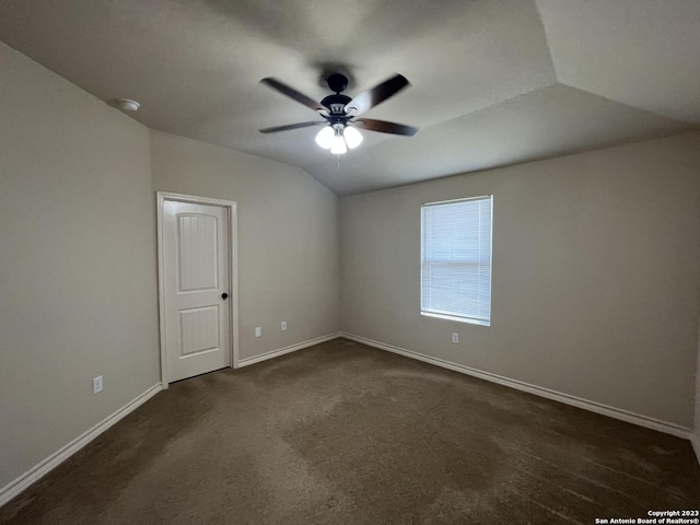 empty room with lofted ceiling, dark carpet, and ceiling fan