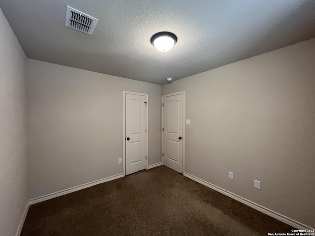 carpeted empty room with a textured ceiling