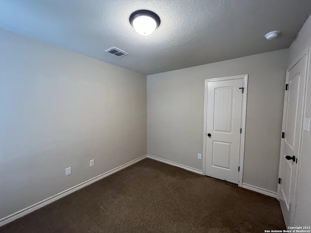 carpeted empty room with a textured ceiling