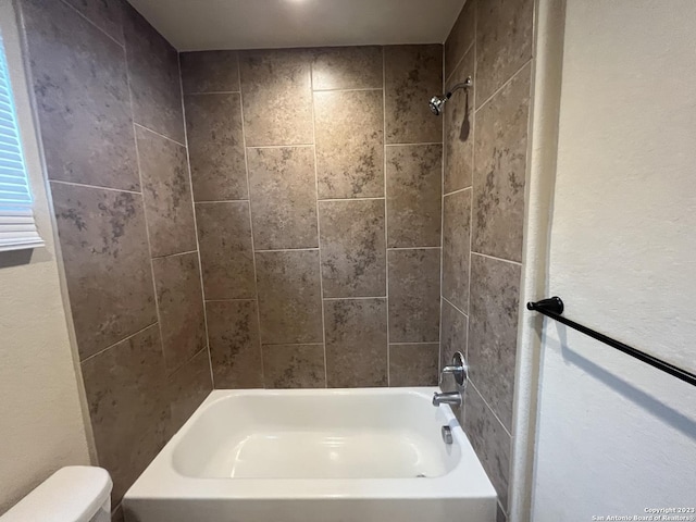 bathroom featuring toilet and tiled shower / bath