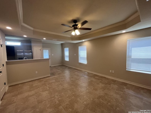 spare room with ceiling fan, crown molding, and a raised ceiling