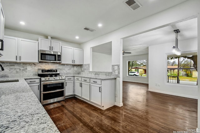 kitchen featuring white cabinets, stainless steel appliances, tasteful backsplash, and hanging light fixtures