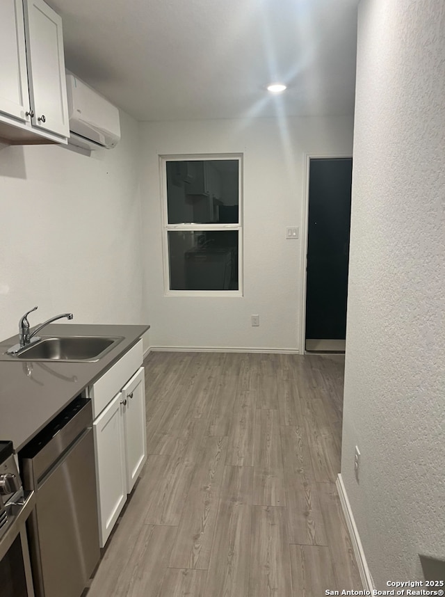 kitchen featuring sink, stainless steel dishwasher, white cabinetry, and light wood-type flooring