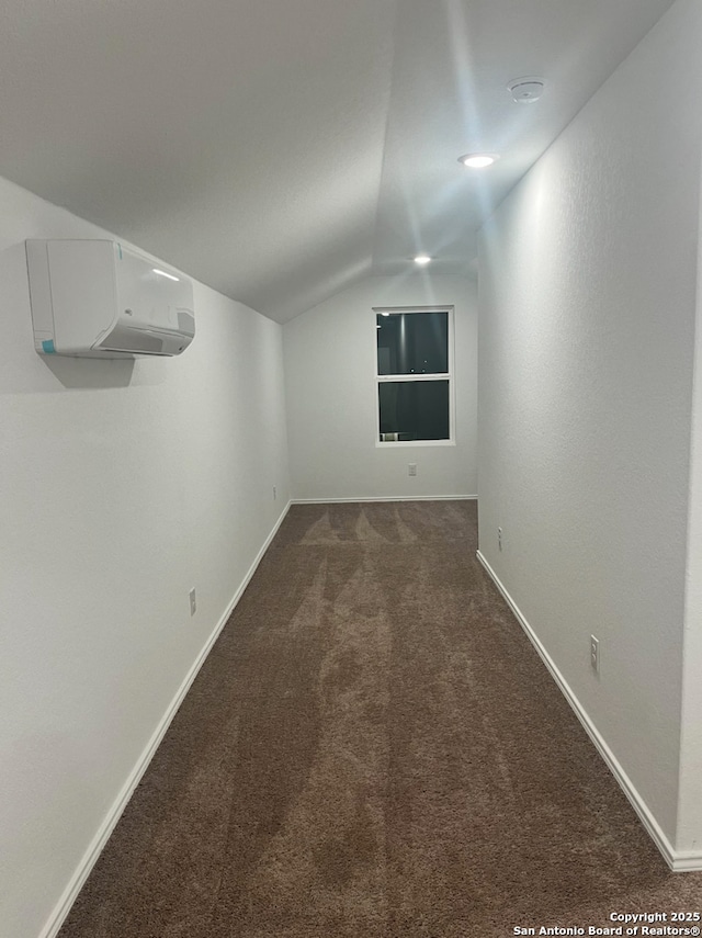 interior space featuring lofted ceiling, an AC wall unit, and dark carpet