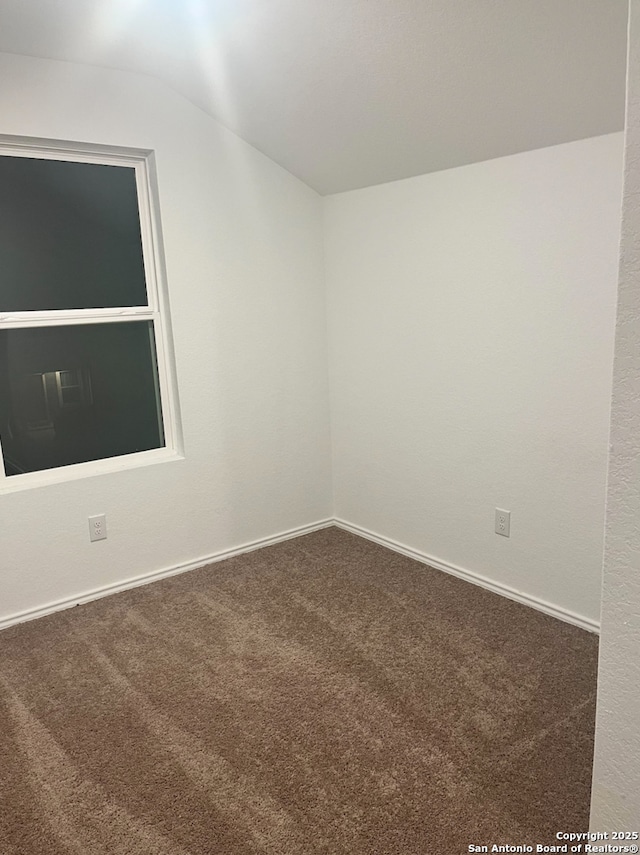 unfurnished room featuring lofted ceiling and carpet