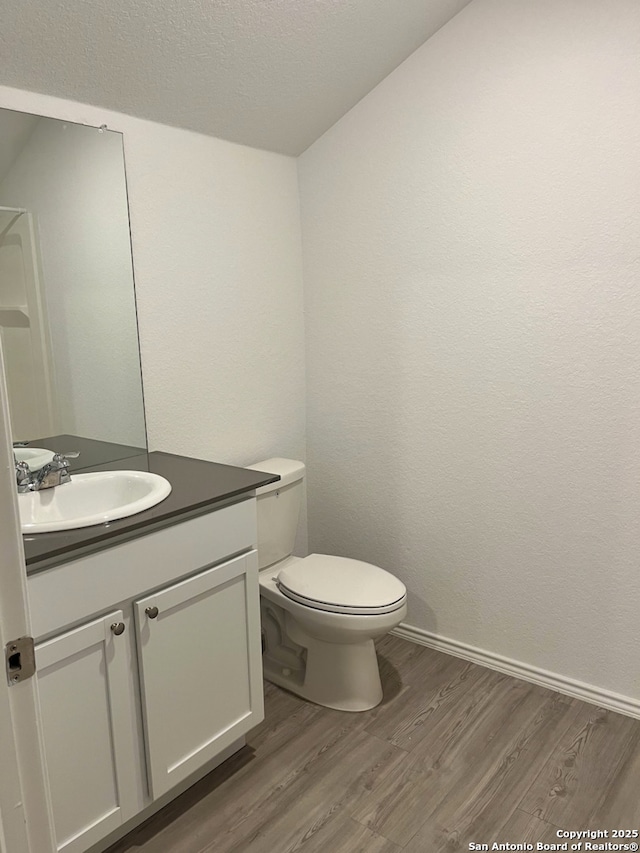 bathroom featuring a textured ceiling, hardwood / wood-style floors, vanity, and toilet