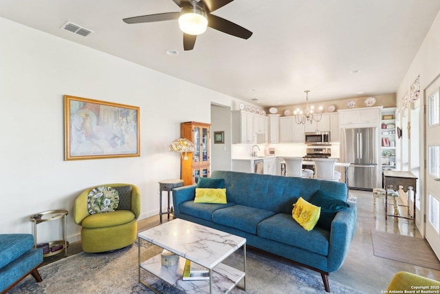 living room with ceiling fan with notable chandelier and sink