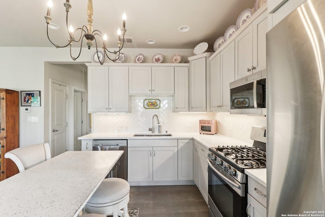 kitchen featuring decorative light fixtures, white cabinetry, stainless steel appliances, sink, and backsplash