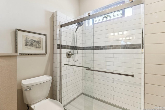 bathroom featuring toilet and a shower with door