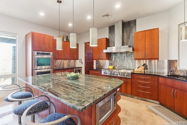 kitchen with backsplash, wall chimney range hood, a kitchen island, sink, and stainless steel appliances