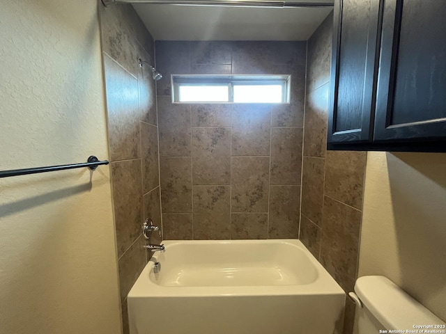 bathroom with toilet and tiled shower / bath