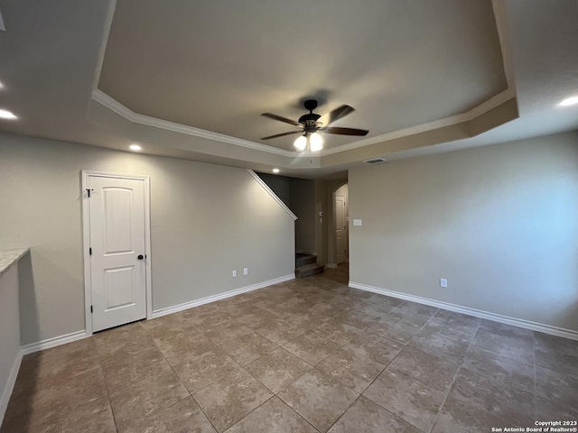 empty room featuring ceiling fan, ornamental molding, and a tray ceiling