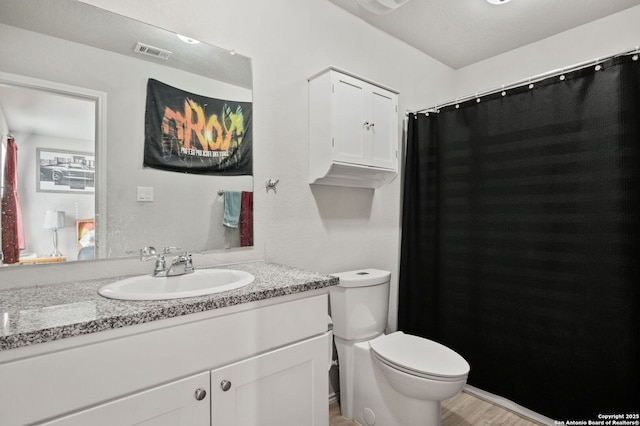 bathroom with toilet, vanity, and hardwood / wood-style floors