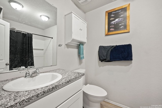 bathroom featuring toilet, a textured ceiling, curtained shower, and vanity