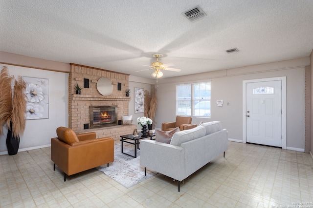 living room with a brick fireplace, a textured ceiling, and ceiling fan