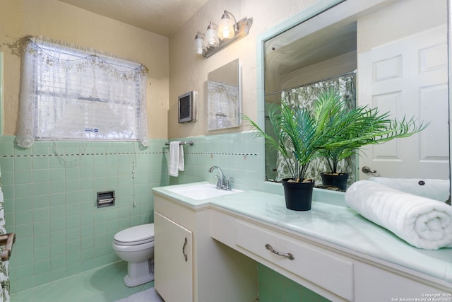 bathroom featuring toilet, tile patterned floors, vanity, and tile walls