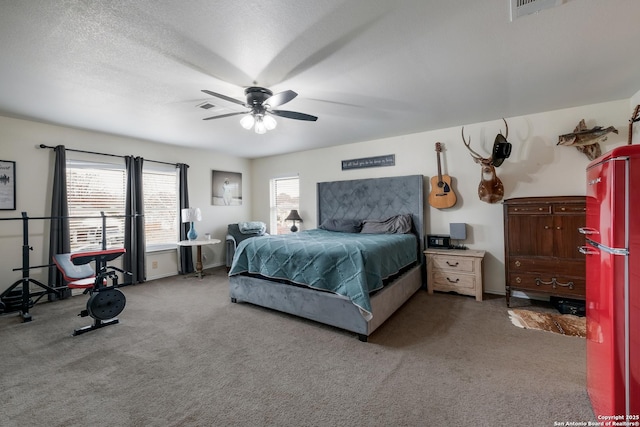 bedroom featuring ceiling fan, refrigerator, multiple windows, and carpet flooring