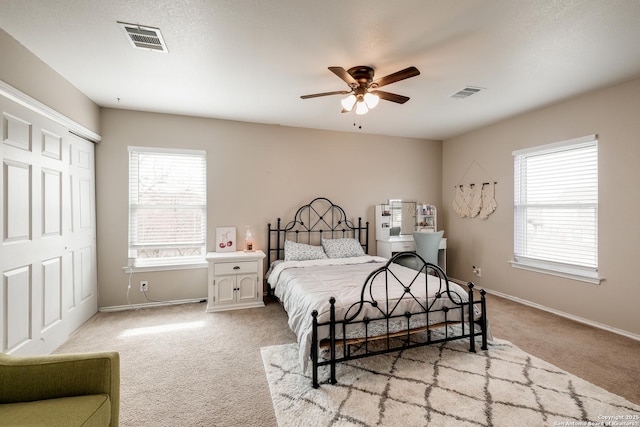 carpeted bedroom featuring multiple windows, a closet, and ceiling fan