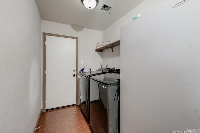 clothes washing area with light hardwood / wood-style floors and independent washer and dryer