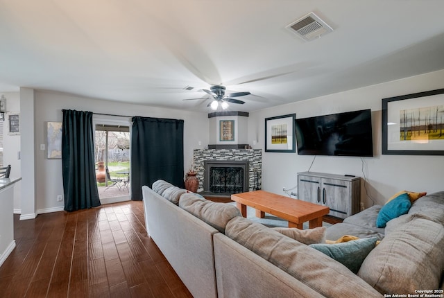 living room featuring dark hardwood / wood-style flooring, a tiled fireplace, and ceiling fan