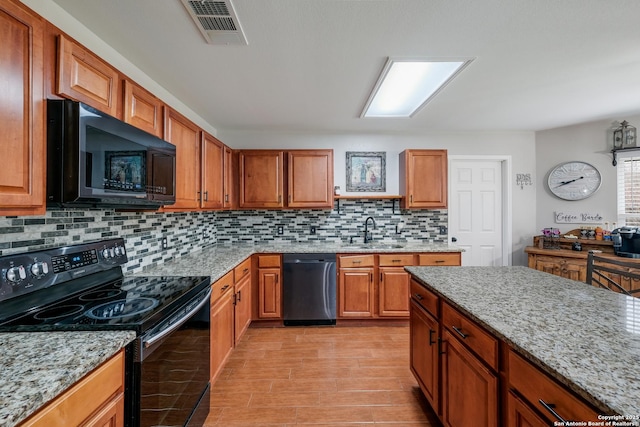 kitchen featuring sink, tasteful backsplash, black appliances, and light stone counters