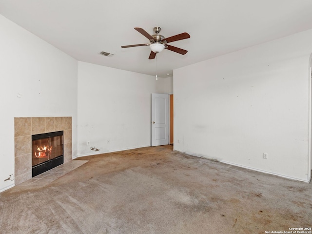 unfurnished living room with light colored carpet, a tiled fireplace, and ceiling fan