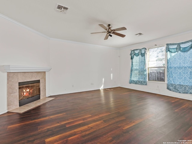 unfurnished living room with a tiled fireplace, ceiling fan, crown molding, and dark hardwood / wood-style flooring