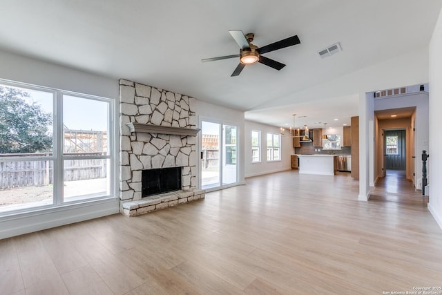 unfurnished living room with light hardwood / wood-style floors, ceiling fan with notable chandelier, vaulted ceiling, and a fireplace