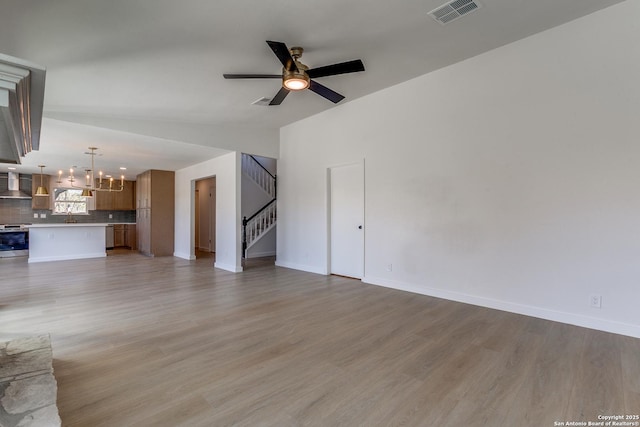 unfurnished living room featuring ceiling fan with notable chandelier, lofted ceiling, and hardwood / wood-style floors