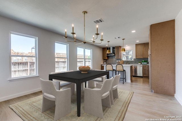 dining room featuring sink, a notable chandelier, and light hardwood / wood-style flooring