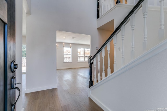 foyer entrance with a high ceiling, a notable chandelier, and wood-type flooring