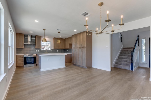 kitchen with a center island, wall chimney exhaust hood, decorative backsplash, electric stove, and pendant lighting