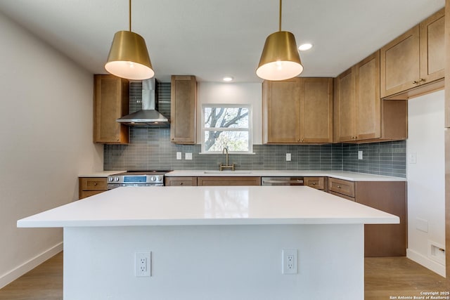 kitchen featuring sink, a kitchen island, wall chimney range hood, and appliances with stainless steel finishes