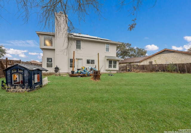 rear view of property with a lawn and a fenced backyard