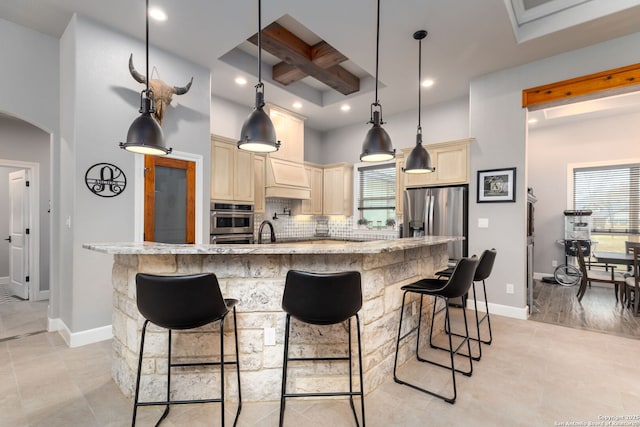 kitchen featuring appliances with stainless steel finishes, hanging light fixtures, a center island, beamed ceiling, and tasteful backsplash