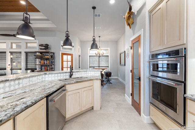 kitchen featuring light stone counters, pendant lighting, stainless steel appliances, light tile patterned floors, and sink