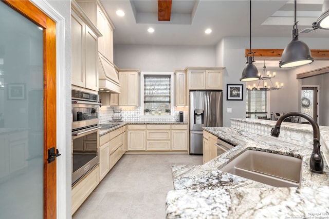 kitchen with light stone counters, decorative light fixtures, an inviting chandelier, appliances with stainless steel finishes, and sink