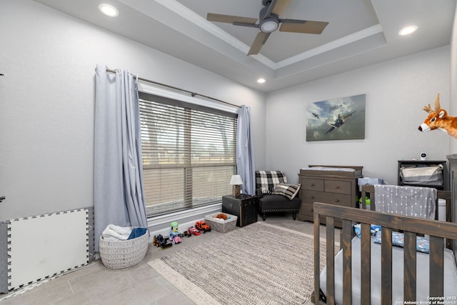 tiled bedroom with a nursery area, a raised ceiling, ornamental molding, and ceiling fan