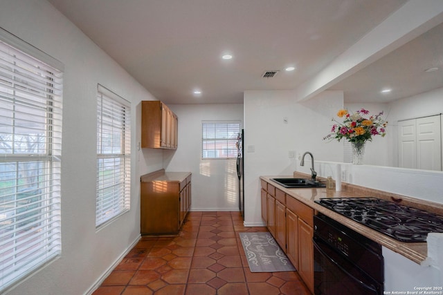 kitchen with black appliances, dark tile patterned flooring, and sink